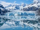 Alaskan glacier and snowy mountains reflected in calm water